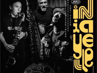 Schwarzweißbild von drei Musikern mit Saxophon, Kora und Mikrofon in dunkler Umgebung
